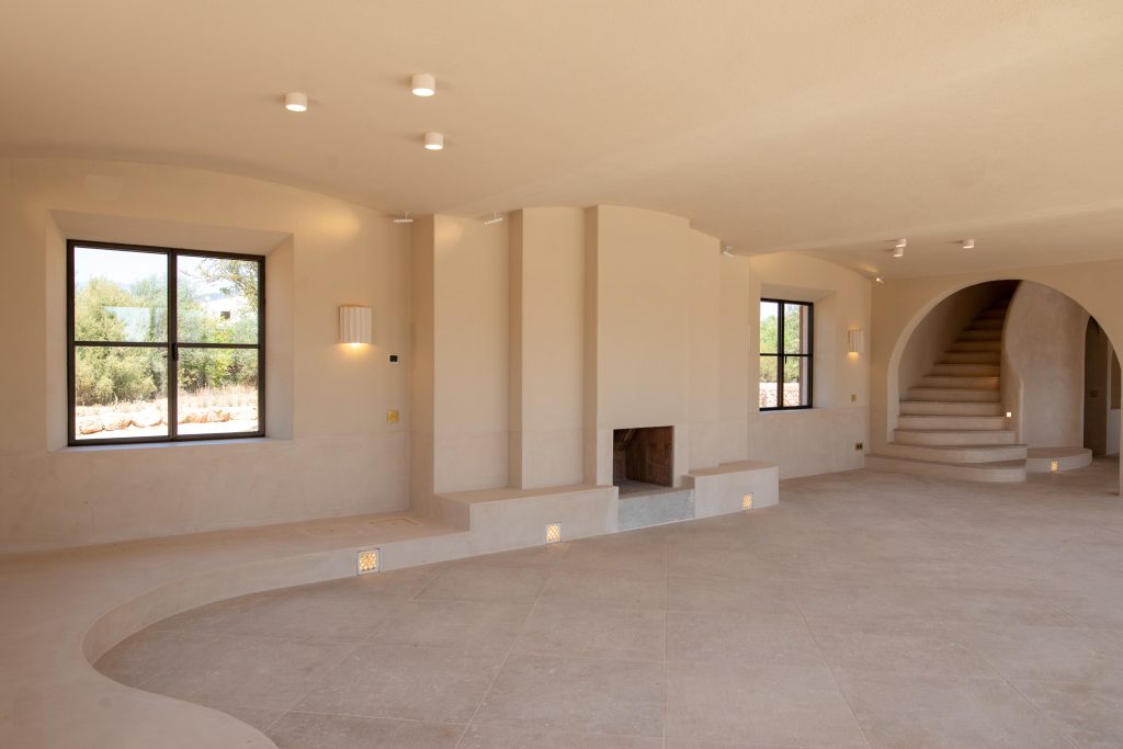 Living room with fireplace and curved staircase in Santa Maria del Camí