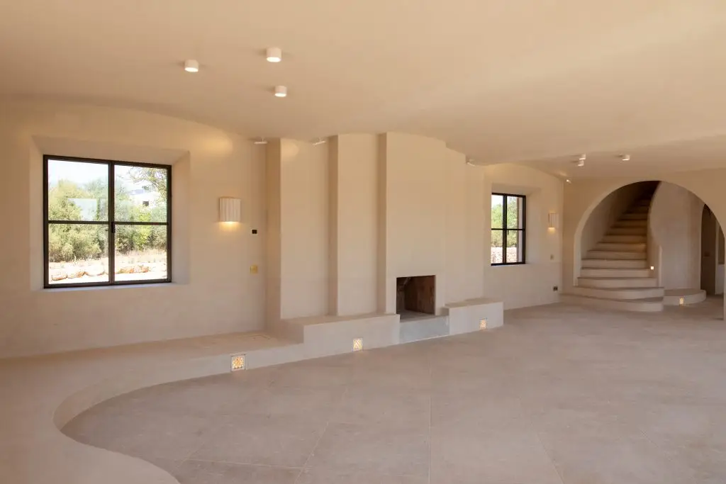 Salón con chimenea y escalera curva en Santa María del Camí
