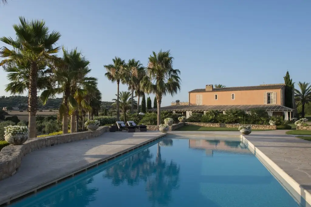 Piscina con vistas a la casa y al jardín de palmeras de Finca Son Naava en Montuïri